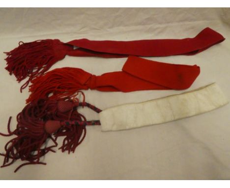 Two military scarlet cloth ceremonial sashes with tassled ends and a similar blanco fabric military sash with scarlet tassles