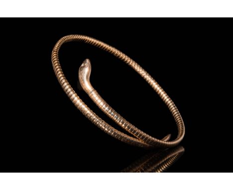 .An Egyptian revival gold bracelet with a twisted snake shaped body. Decorated with scales and a detailed head. Size: 120mm x