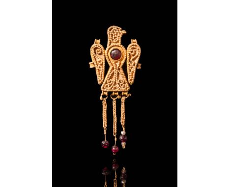 Ca. AD 300 - 600.A late Roman or Early Byzantine 20.5 ct gold legionary eagle-shaped pendant decorated with a red cabochon se