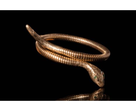 .An Egyptian revival gold bracelet with a twisted snake shaped body. Decorated with scales and a detailed head with emeralds 