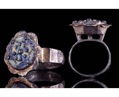 European, Ca. AD 1400.A silver gilt ring featuring a beautiful floral-shaped bezel with raised bosses and remnants of blue an