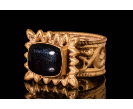 Ca. AD 500 - 700.An early Byzantine 20.5 ct gold ring with a rectangular garnet cabochon. The band is decorated with openwork