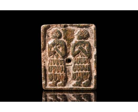 Ca. 2500 BC.A stone stamp seal, perforated at the centre, features a raised border encapsulating a scene depicting two standi