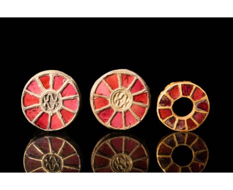 Ca. AD 500 - 700.A collection of three Merovingian inlaid disc brooches, composed of an outer border of stepped cells filled 