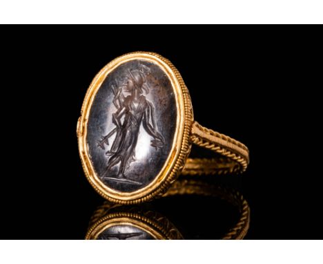 Ca. AD 100 - 300 .A Roman smoky quartz intaglio depicting Mars holding a stylised mace. The intaglio is set in a high carat (