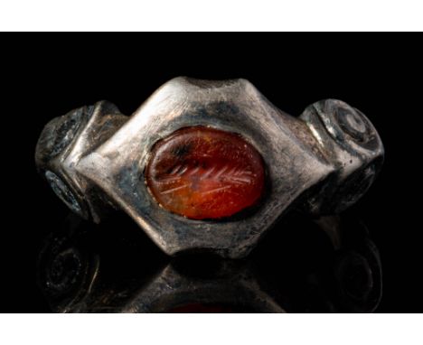 Ca. AD 100 - 300.A Roman silver ring with the band decorated by floral motifs and an oval intaglio depicting a profile of a s