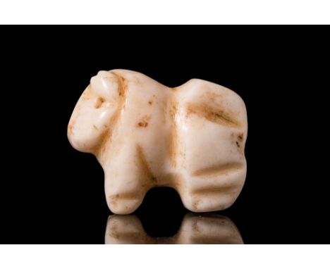 Ca. 3500 - 2900 BC.A Sumerian white stone amulet in the form of a standing bull, with curved horns, drilled eyes and an incis