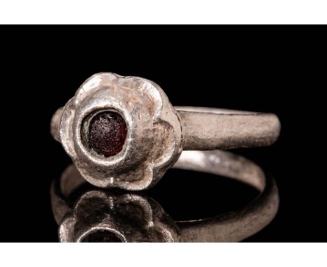 Ca. AD 1400 - 1500.A Western European Medieval silver ring with glass cabochon set in a flower shaped bezel. it has six petal