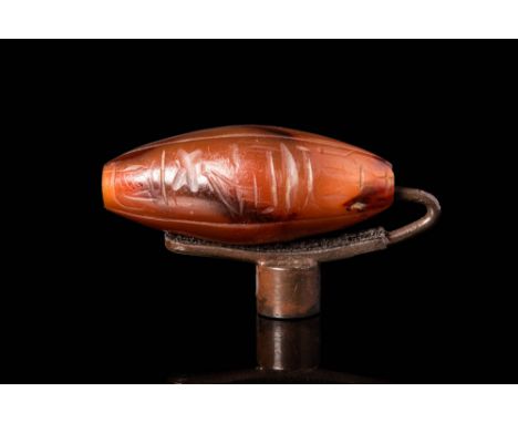 Ca. 1550 - 1069 BC.A ritual carnelian bead with fiery citrine hues and scattered areas of crimson inclusions. The almond shap