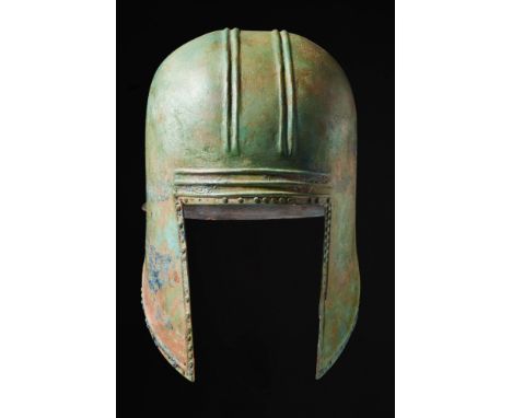 Late Archaic period, Ca. 500 BC. A rare domed helmet with long pointed cheek guards and rectangular face opening. Raised para