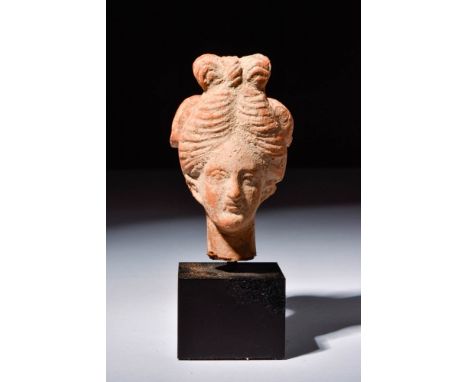 Ca. 400 - 300 BC.A mould-made terracotta head of aphrodite. Her hair is arranged in a wide bipartite chignon at the nape of h