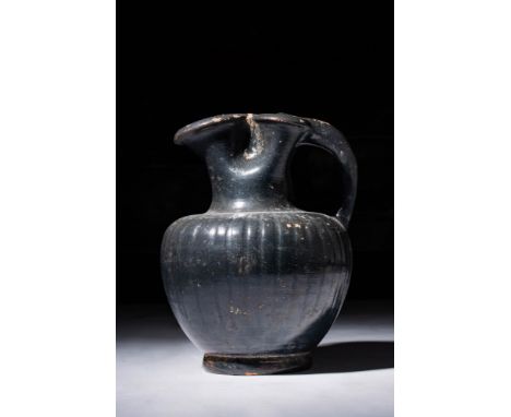 Ca. 330 - 300 BC.A Greek black glazed trefoil oinochoe with a decorated ovoid body dipping slightly at the shoulders toward t