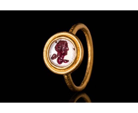 Ca. AD 300 - 400 .A Roman 21.5 ct gold ring with a garnet intaglio depicting a head of Cupid facing right. The details of the