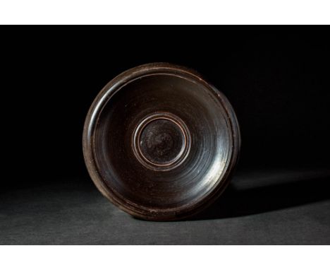 Ca. 400 - 300 BC.A Greek Apulian black glazed fish plate. The edges of the central depression and the rim are each adorned wi