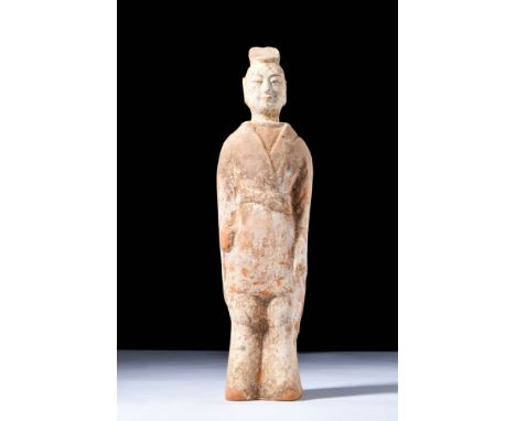 Northern Wei, Ca. AD 386 - 534.A terracotta attendant figure dressed in a tunic and trousers with a waist sash. Good conditio