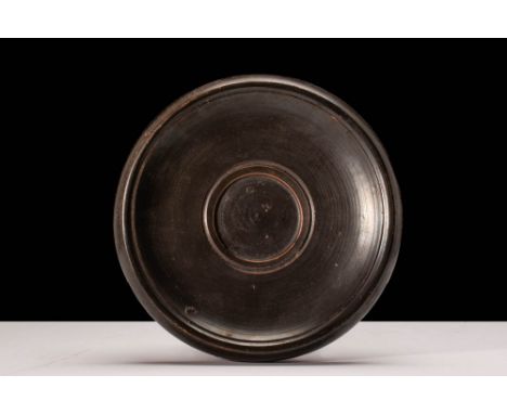 Ca. 400 - 300 BC.A Greek Apulian black glazed fish plate with a gently sloping bowl and overhanging rim. The edges of the cen