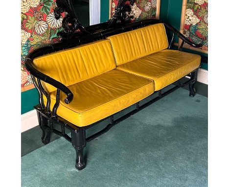A Chinese style black painted faux bamboo two seater settee, having yellow cushions, 175cm wide