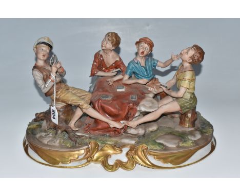 A CAPODIMONTE PORCELAIN FIGURE GROUP OF FOUR BOYS PLAYING CARDS on a naturalist base, a gilt scrolling acanthus batten on the