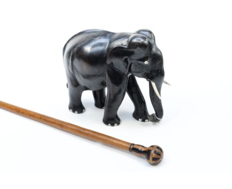 An ebonised elephant with an inlaid walking stick 