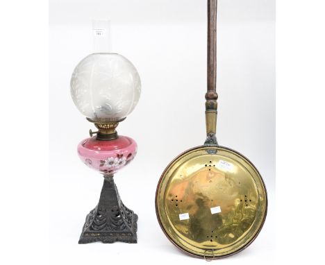 A Victorian oil lamp with cast base and warming pan (2) warming pan displayed by metalware shelves