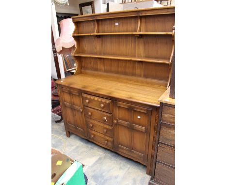 An Ercol elm dresser with rack, the rack section fitted with two plate shelves, the base with two doors and four drawers