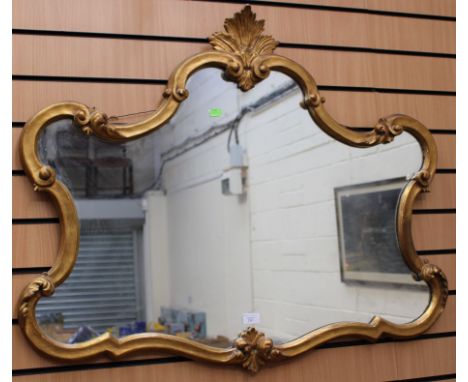 A Rococo style gilt framed mirror, the top with acanthus leaf finial, fitted with plain glass