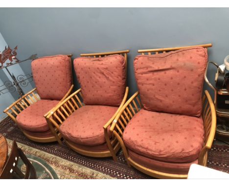 A set of three light elm Ercol elbow chairs with pad upholstered seats and back