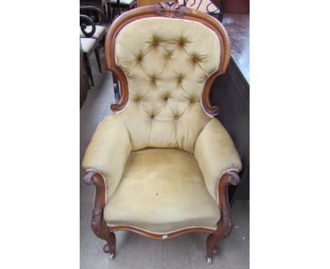 A Victorian mahogany framed spoon back library chair with button back upholstery, carved cresting rail, arm terminals and leg