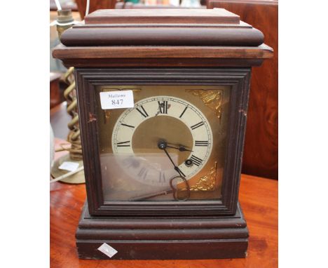 AN AMERICAN ANSONIA CLOCK COMPANY MANTLE CLOCK with dark stained case, brass dial and roman numerals, 24cm wide x 33cm high