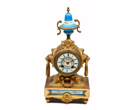 A GILT METAL AND PORCELAIN MOUNTED MANTLE CLOCK, the case with lion mask and laurel wreath ring handles and urn finial, the p