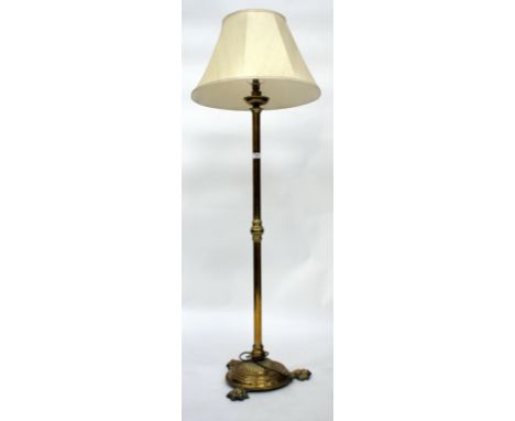 A VICTORIAN BRASS STANDARD LAMP with fluted cylindrical base and three paw feet together with a shade, overall 140cm high