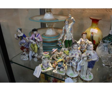 A PAIR OF DERBY STYLE PORCELAIN FIGURINES of a gentleman playing a pipe and his female companion with an apron full of flower