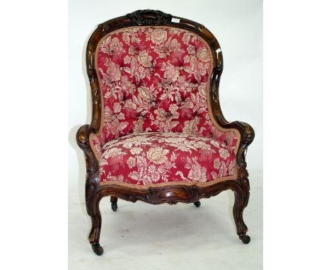 A VICTORIAN WALNUT SPOON BACK LIBRARY CHAIR with carved frame and red button upholstered back standing on carved legs with ce