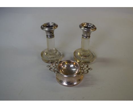 A silver tea strainer on stand, by Marson & Jones, Birmingham 1934; together with a pair of silver mounted glass candlesticks