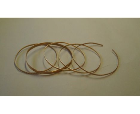 Four 9ct gold bangles, 18g; together with a similar unmarked bangle.