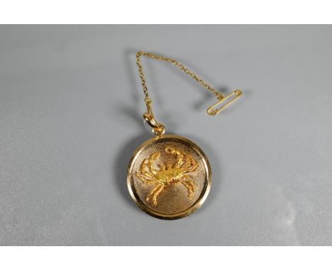 A circular yellow metal pendant disc featuring a naturalistically detailed crab in relief on engine turned base, stamped 750,