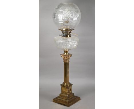 A late 19th century brass Corinthian column style cast oil lamp with clear cut-glass reservoir and shade, 73 cm h o/all (conv