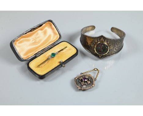 An Arts &amp; Crafts style bangle with hammered finish and central mounted stone boss with beadwork decoration around, white 