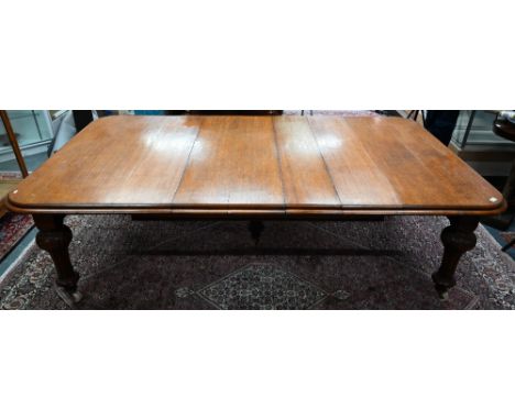 A large Victorian golden oak extending table, the wind action top with rounded corners accepting the six extension leaves (in