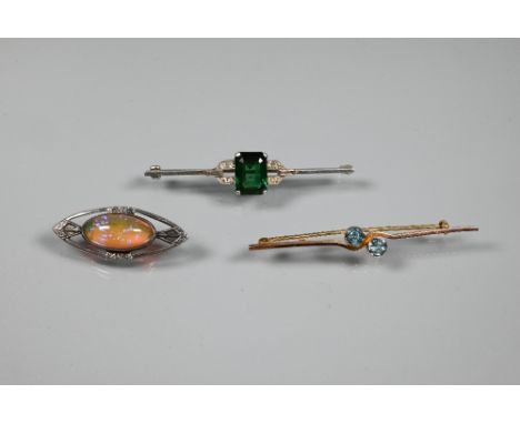 An Art Deco bar brooch in unmarked white metal set with central rectangular green stone with small round and baguette cut dia