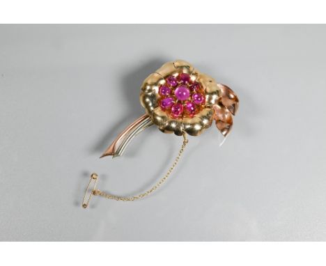 A floral spray brooch of pink, yellow and white unmarked metal set with nine pink sapphire/ruby cabochon stones in the form o