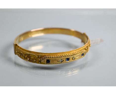 An Edwardian 9ct yellow gold bangle of oval half-hinged form, with applied bead and rope-style decoration, concealed clasp fi