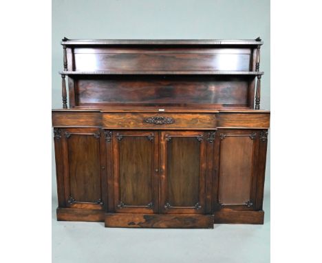 An early Victorian rosewood breakfront chiffonier, the two tier graduated open shelf over three frieze drawers and four cupbo