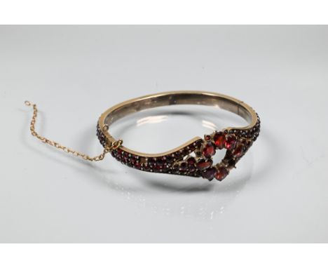 A Victorian half-hinged bangle set overall with garnets (possibly), silver-gilt, in as found condition with missing stones et