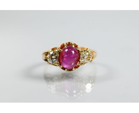 A three stone ring, the central oval cabochon ruby with circular diamond to each side, claw set, unmarked yellow gold, size M