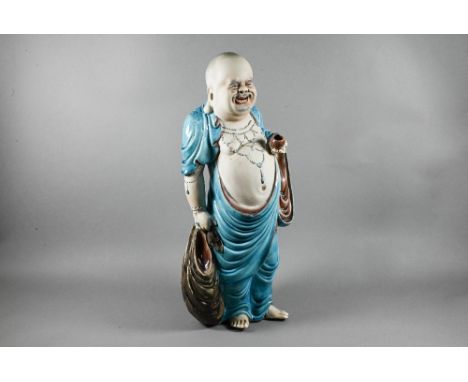 A 20th century Chinese part-glazed bisque porcelain figure of Budai Hehang (Laughing Buddha) modelled with jovial expression,