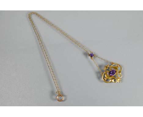An Art Nouveau pendant, the 9ct yellow gold open scroll design with central oval shaped amethyst, suspended from chain, appro