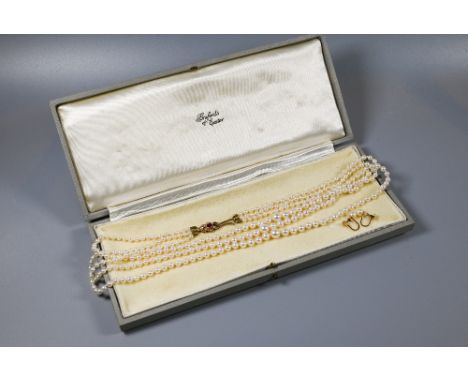 A triple row of graduated cultured pearls double knotted throughout onto ruby and pearl set snap, 9ct yellow gold, approx 49 