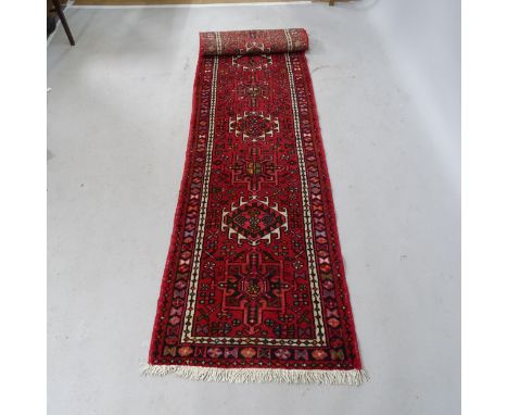 A red-ground Afghan design runner. 286cm x 63cm 