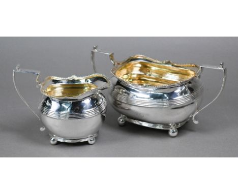 A Regency silver milk jug and sugar basin with moulded rims, gilt interiors and scroll handles, on ball feet,&nbsp;Alice &amp